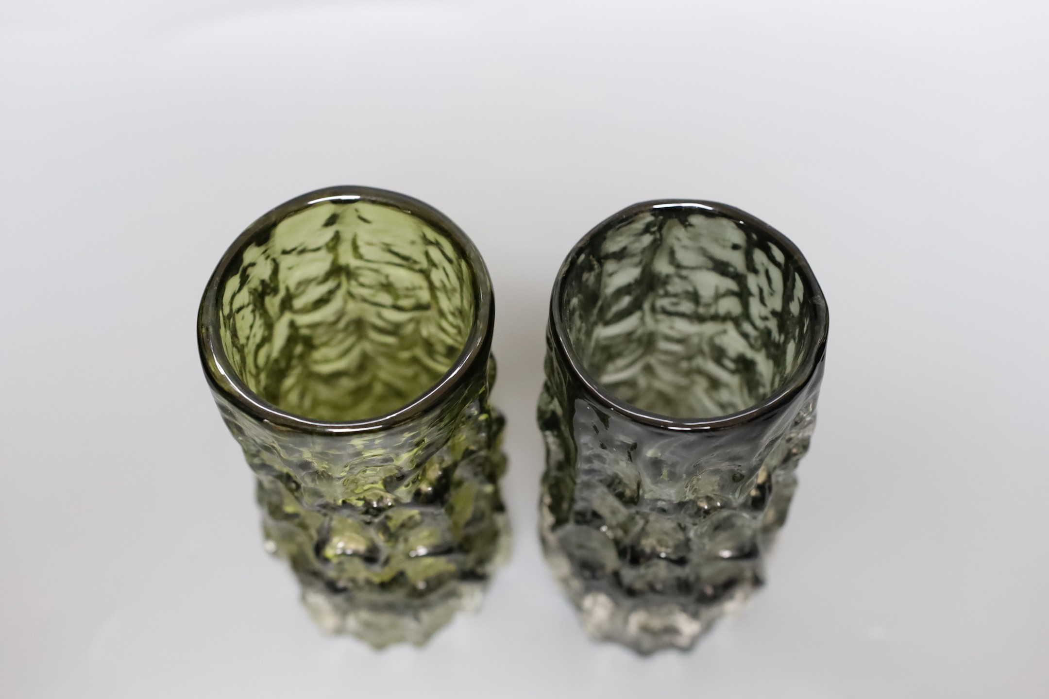 Two Whitefriars 'bark' cylinder vases, model 9689 designed by Geoffrey Baxter in ‘sage’ and 'willow' glass, each 15cm high.